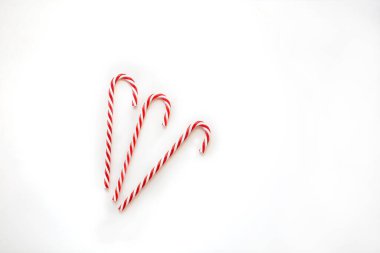 Noel kompozisyonu. Beyaz arka planda üç çizgili baston. Model ve projeniz için minimalist bir konsept. Düzen, düz yatış, kopyalama alanı, üst görünüm. 