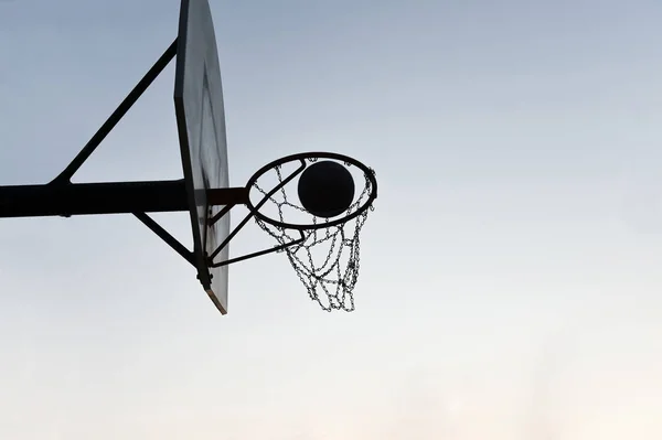 Silhouette bir basketbol çember ve gün batımında sedye