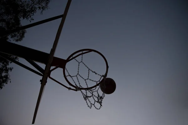 Silhouette bir basketbol çember ve gün batımında sedye