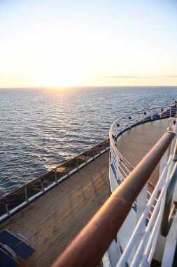 Okyanusun içinde belgili tanımlık geçmiş ile gün batımında korkuluk ve güverte döşeme bir cruise gemi.