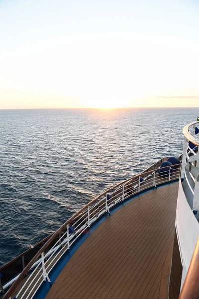 Okyanusun içinde belgili tanımlık geçmiş ile gün batımında korkuluk ve güverte döşeme bir cruise gemi.