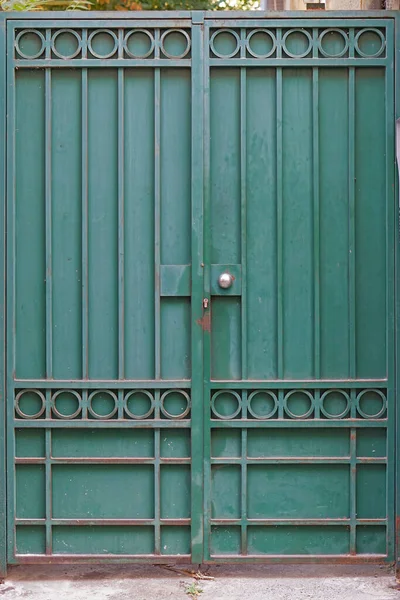 Green metal gate double doors closed