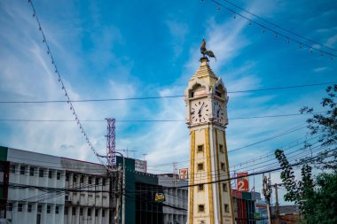 Tanam Nonthaburi, Tayland mavi gökyüzüne karşı dağınık bir elektrik teli ile sarı saat kulesi üzerinde tavuk heykeli