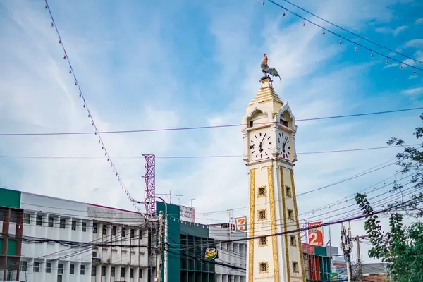 La estatua de pollo en la torre del reloj amarillo con un alambre de electricidad desordenado contra el cielo azul en Tanam Nonthaburi, Tailandia — Foto de Stock