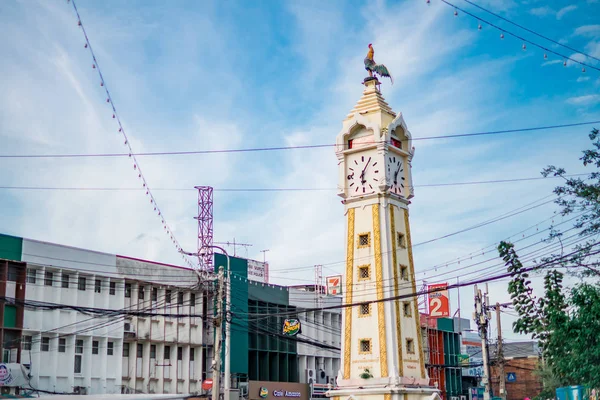La estatua de pollo en la torre del reloj amarillo con un alambre de electricidad desordenado contra el cielo azul en Tanam Nonthaburi, Tailandia — Foto de Stock