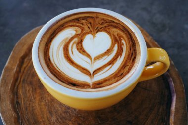 Bir bardak kapuçino ve ahşap tabakta güzel bir latte tabağı. Anne!