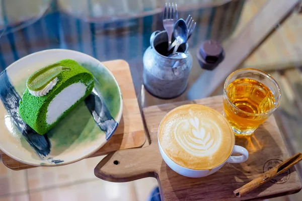 Bir bardak cappuccino ile ahşap tabakta güzel latte sanatı, yeşil