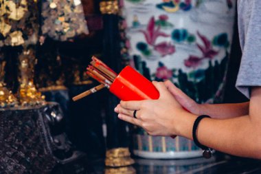 Yakın el ele tutuşan kadın Chi-Chi Çubukları ya da Tayland tapınağında dikişleri sallıyor, çubuklardan biri şans ve umut, Din, Tayland.