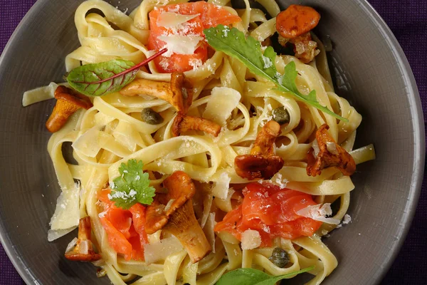 Tasty pasta with salmon and chanterelles top view