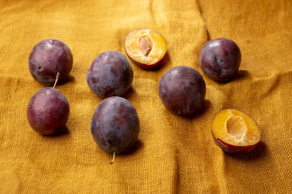 Ripe plums on yellow background