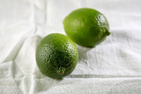 Zwei grüne Limetten auf weißem Stoff — Stockfoto