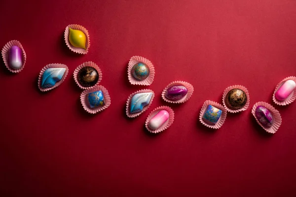 Moderne kleurrijke bonbons op rood papier — Stockfoto