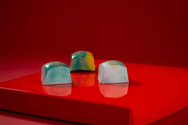 Trois bonbons au chocolat sur fond rouge — Photo