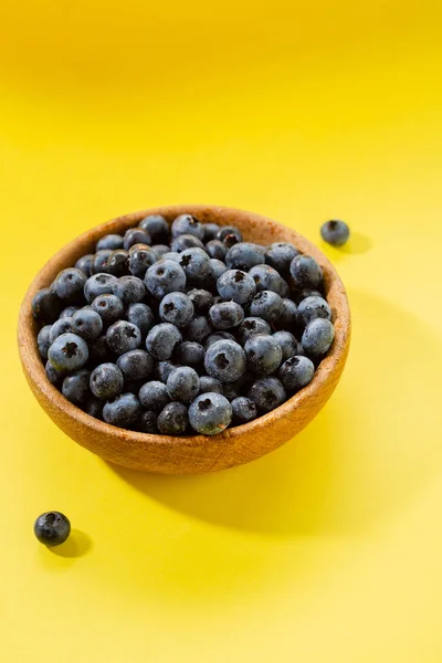 Frische Blaubeere in Holzschale auf gelbem Hintergrund — Stockfoto