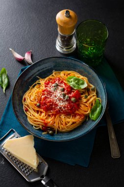 Siyah masada kırmızı domates soslu ve peynirli spagetti.