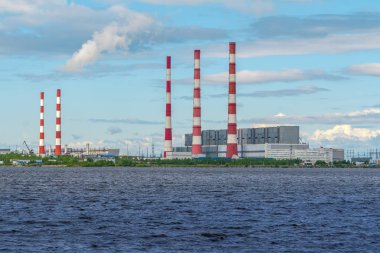Parlak güneşli bir günde baraj gölünün kıyısında parlak bacaları ile termik santraller.