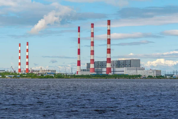 Parlak güneşli bir günde baraj gölünün kıyısında parlak bacaları ile termik santraller.