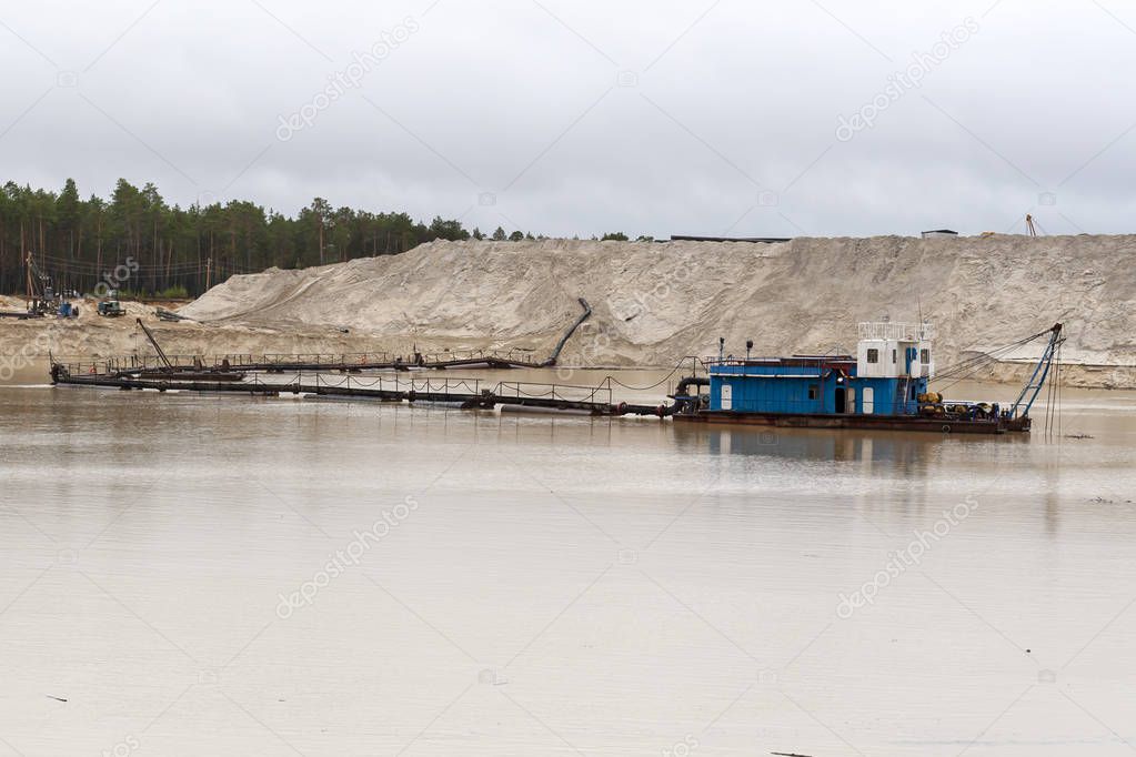 The dredger extracts sand from the quarry in the forest. Interference in the ecology of the forest.