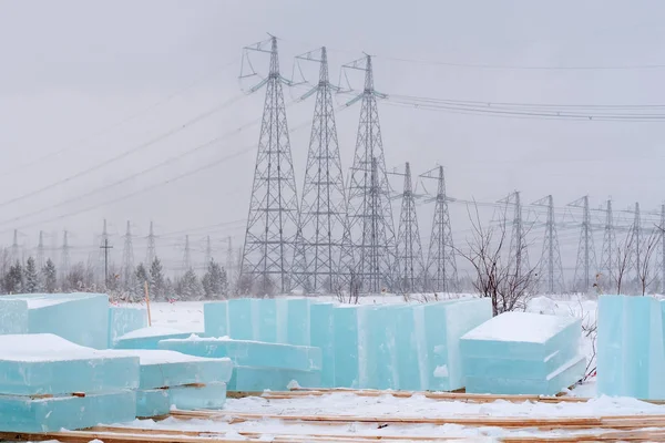 Buz blokları ulaşım için yığılmış. Buz heykeller yapmak için malzeme. Arka planda bir yüksek voltajlı güç çizgidir.