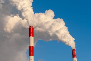 Borular, soğuk kış gününde, termik santraller yakın çekim. Termik santral yüksek borular Beyaz kalın duman. Bir soğuk kış gününde beyaz bir mavi gökyüzü üstünde buhar.