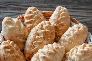 Ahşap bir masa, closeup üzerinde bir hasır sepet'lezzetli, kırmızı börekleri.