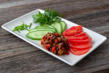 Vejetaryen yemek. Sebze meze patlıcan Yapıştır dilimlenmiş salatalık, domates ve bir dikdörtgen beyaz tabak içinde otlar ile dekore edilmiş.