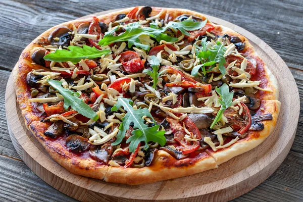 Vegetarian dish. Vegetarian pizza with tofu, mushrooms, tomatoes, olives and arugula. Healthy food.