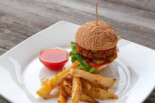 Healthy diet. Vegan Burger, ingredients: sesame bun, Patty of chickpeas, chili, tomatoes, pickles, tomato sauce and baked potatoes with herbs.