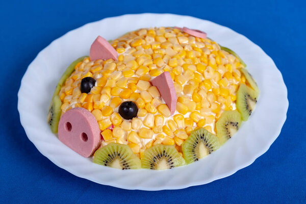 Corn salad in the style of the New year-the year of the Yellow Pig. Symbol of the new 2019 on the Chinese horoscope. Festive meal. Salad in the form of a cute pig on a blue background.