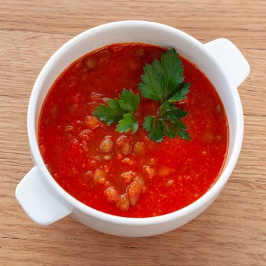 Vejetaryen yemek. Domates-mercimek çorbası, otlar ile dekore edilmiştir. Malzemeler: domates, kendi suyu, mercimek, soğan, baharat. Kare biçimi.