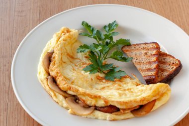 Vejetaryen yemek. Otlar ve tost ile dekore edilmiş mantarlı omlet.
