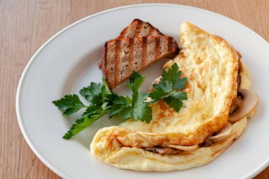 Vejetaryen yemek. Otlar ve tost ile dekore edilmiş mantarlı omlet.