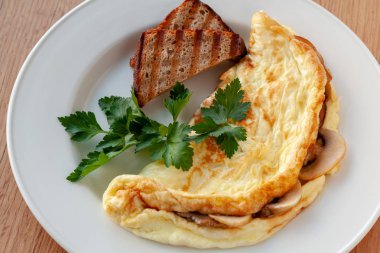 Vejetaryen yemek. Otlar ve tost ile dekore edilmiş mantarlı omlet.