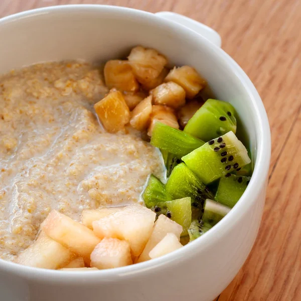 Raw food dish. Wheat porridge with coconut milk, Jerusalem artichoke juice, decorated with fruit. Vegetarian dish. Square format. Close up.