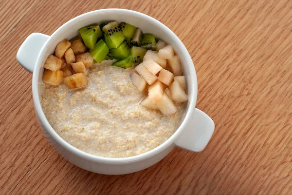 Raw food dish. Wheat porridge with coconut milk, Jerusalem artichoke juice, decorated with fruit. Vegetarian dish.