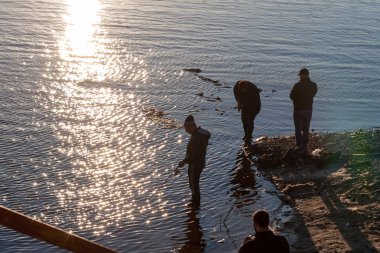 İnsanlar güneşte balık tutar. Karşı balıkçıların siluetleri