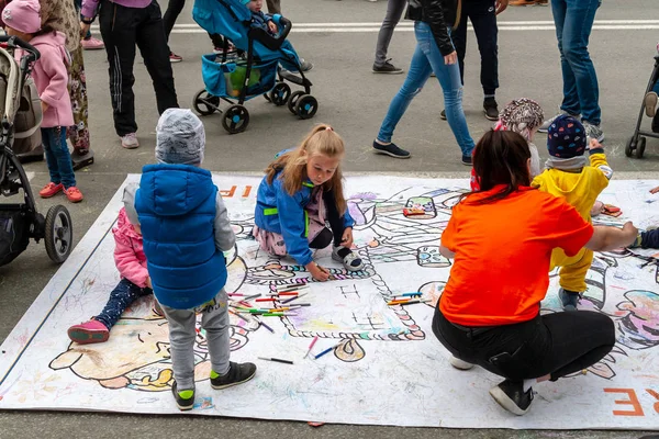 子供たちは色付きのマーカーで床に描きます。フェスティバルで子どもたちのアクティブなエンターテイメント. — ストック写真