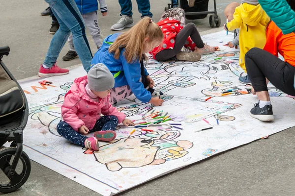 子供たちは色付きのマーカーで床に描きます。フェスティバルで子どもたちのアクティブなエンターテイメント. — ストック写真