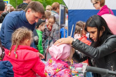 küçük bir kızın yüzünde vücut sanatı, Rusya Günü kutlama.Little kızlar vücut sanatı örnekleri ile bir katalog düşünüyor.