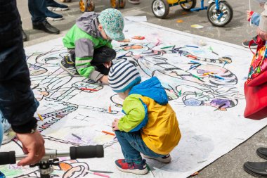  Çocuklar renkli işaretlerle yere çizerler. Festivalde çocukların aktif eğlencesi.