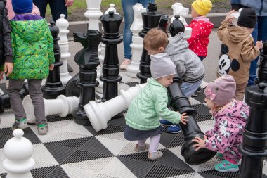 Çocuklar büyük bir satranç tahtası üzerinde dev satranç taşları ile oynamak.