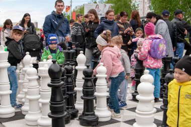 Çocuklar büyük bir satranç tahtası üzerinde dev satranç taşları ile oynamak.