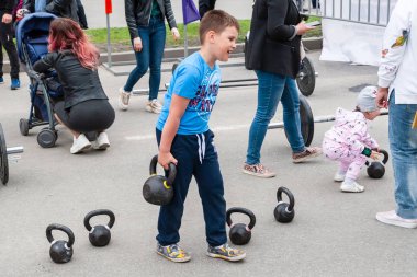 Festivaldeki çocuklar ağırlık ve halter kaldırıyor.