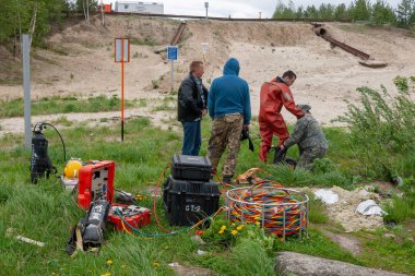 Dalış işi. Asistanlar dalgıç dalış önce sahilde bir uzay elbisesi koymak için yardımcı olur.