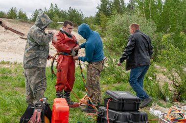 Asistanlar bir uzay elbisesi koymak için dalgıç yardımcı olur.