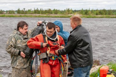 Destek ekibi, dalgıcın derin deniz çalışmalarına hazırlanmasına yardımcı olur..