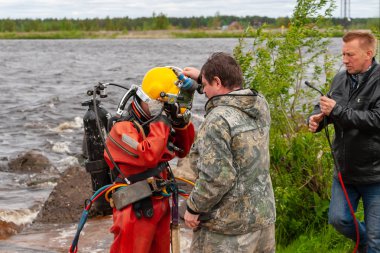 Destek ekibi, dalgıcın derin deniz çalışmalarına hazırlanmasına yardımcı olur..