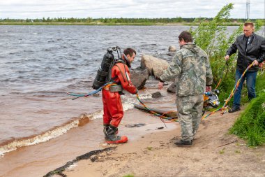 Destek ekibi, dalgıcın derin deniz çalışmalarına hazırlanmasına yardımcı olur..