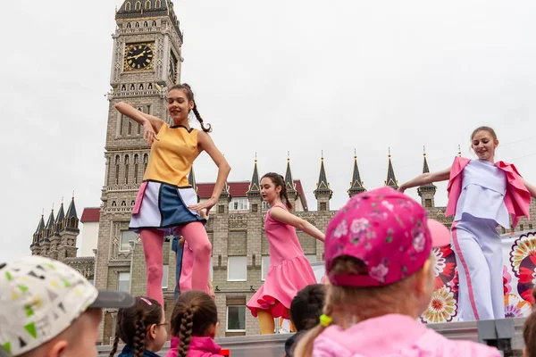 Performance de l'équipe chorégraphique pour enfants lors de la célébration de la fête de la Russie à Surgut, en plein air sur le fond du bâtiment une copie de Londres Big Ben . — Photo