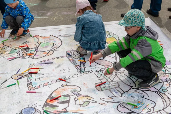 Children draw on the floor with colored markers. Active entertainment of children at the festival. — Stock Photo, Image